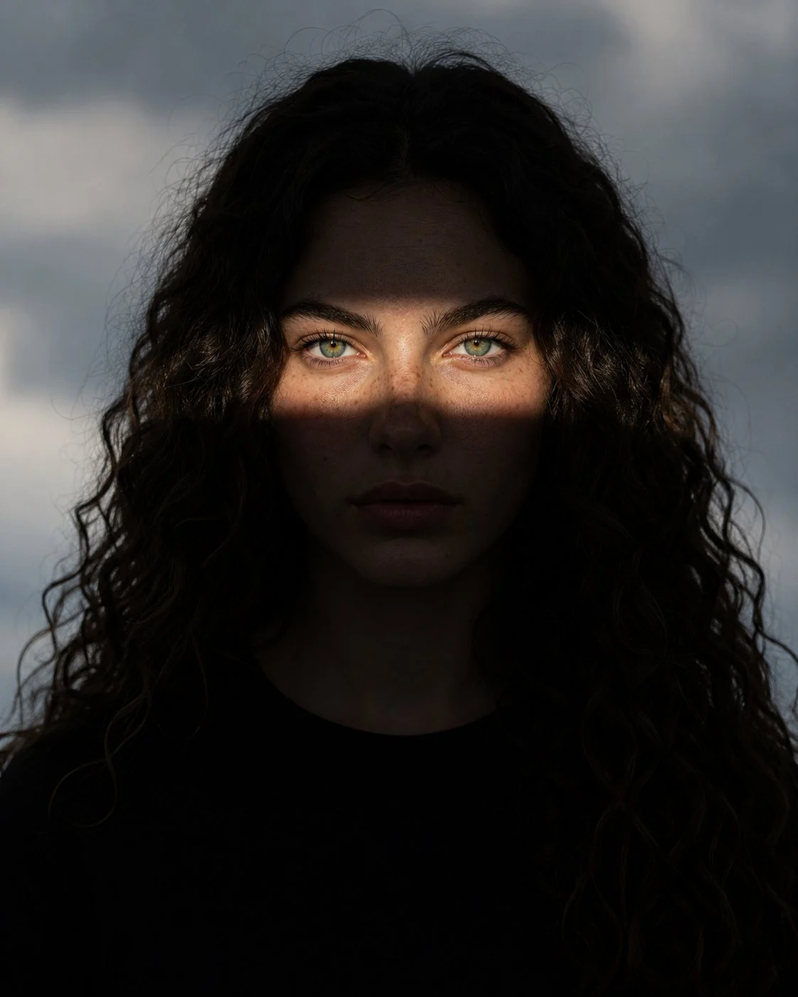 Symmetrical portrait of a woman in near darkness with a single narrow band of sunlight falling across her eyes.