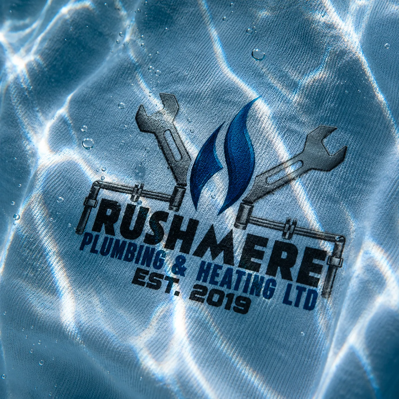 Macro of the Rushmere print on wet cotton: wrenches, flame, and pipework legible at thread distance